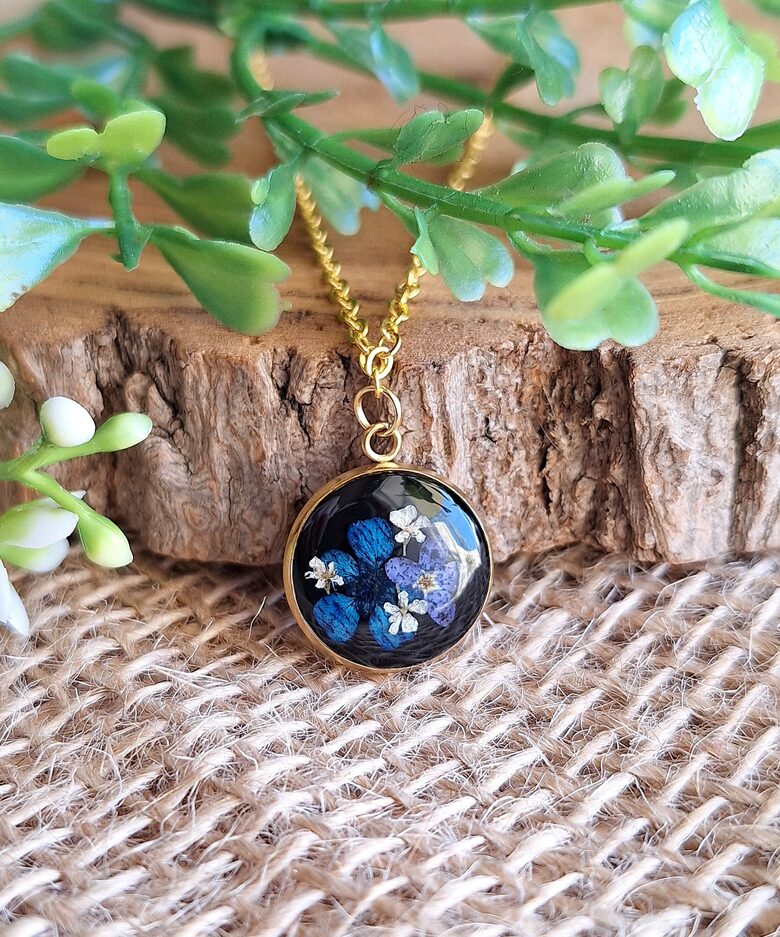 Czarny wisiorek z niebieskimi kwiatami zatopionymi w żywicy - złota stal szlachetna